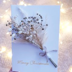 a hand holding a christmas card with dried flowers