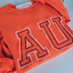 Collegiate Sweatshirt With Embroidered Graphics, Sporty Orange Sweatshirt With Letter Print, Collegiate Orange Tops For Game Day, Orange Ribbed Cuffs Sweatshirt For Fall, Varsity Sweatshirt With Letter Embroidery For College, Varsity Style Campus Top With Letter Embroidery, College Fall Sweatshirt With Letter Patch, Collegiate Crew Sweatshirt With Letter Embroidery, Collegiate Sweatshirt With Embroidered Logo For Fall