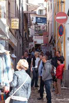 many people are walking down an alleyway with signs on the walls and buildings in the background