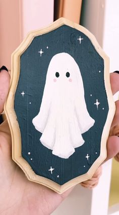 a person holding up a wooden cutout with a ghost on it