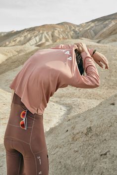 a woman in tights is taking a photo with her cell phone while standing on top of a mountain