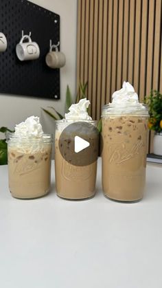 three mason jars filled with whipped cream and toppings on top of a white counter