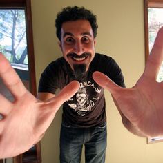 a man making a funny face while holding his hands in front of him with the caption seri tankian