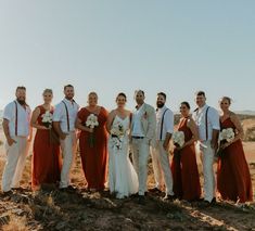 a group of people standing next to each other on a dirt field in the desert