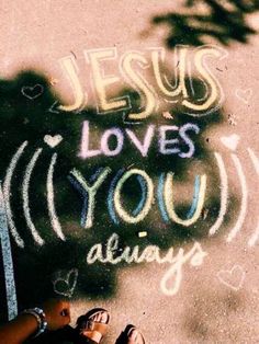 someone's feet on the ground in front of a chalk drawing that says jesus loves you always