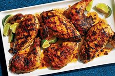 grilled chicken with lime wedges on a white platter, ready to be eaten