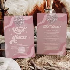 two pink cards with disco balls on them sitting next to each other in front of a white furnishing