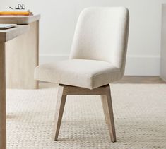 a white chair sitting on top of a wooden table in front of a computer desk