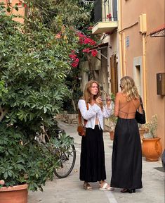 two women standing in the street talking to each other