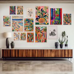 a living room with art hanging on the wall and potted plants next to it