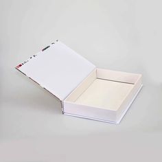 an open book with white paper inside on a gray surface next to a black pen