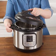 a woman is holding the lid on an electric pressure cooker