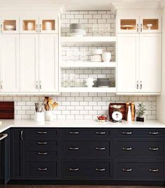 a kitchen with white cabinets and black drawers