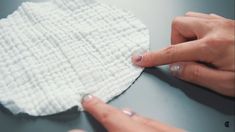 two hands are cleaning a white cloth on a table with one hand pointing at it