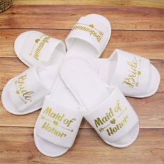 white slippers with gold lettering on them sitting on top of a wooden floor next to a potted plant