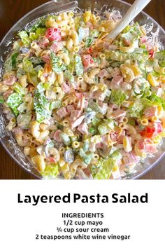 a bowl filled with pasta salad on top of a wooden table