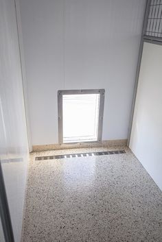 an empty room with a small window on the wall and tile flooring in front of it