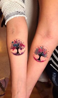 two people with matching tattoos on their legs, both showing the same tree and moon