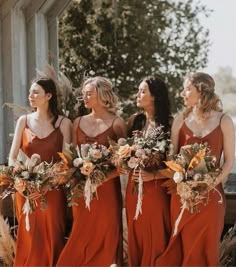 a group of women standing next to each other wearing red dresses and holding bouquets