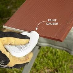 an image of a person using a paint roller to finish a wooden bench with gloves on it