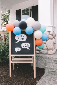 a chalkboard sign with balloons attached to it in front of a white house that says its a friend