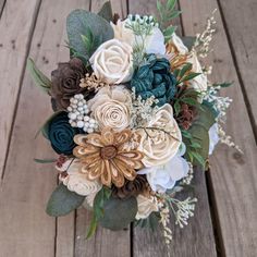 a bridal bouquet on a wooden surface with greenery and flowers in the center