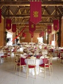 tables and chairs are set up in a large room with red banners hanging from the ceiling