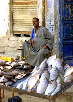 a man sitting in front of a table with fish on it and a hose attached to his mouth