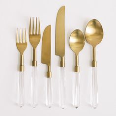 five forks, spoons and knives are lined up against a white background with gold accents