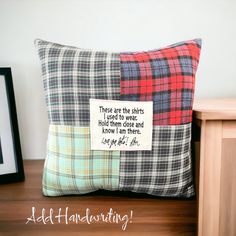 a pillow with a quote on it sitting next to a wooden table and framed photograph