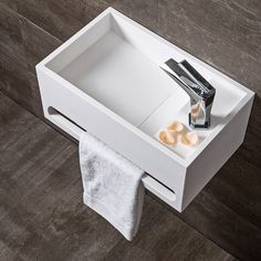 a white sink sitting on top of a wooden floor next to a towel and two toothbrushes