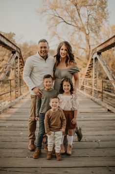 a family standing on a bridge in the fall with one child holding his mom's hand