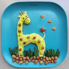 a blue plate with a giraffe made out of rice and nuts