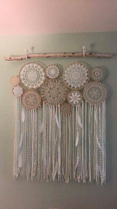 there is a wall hanging made out of doily and wood pieces with feathers on it