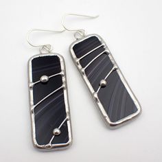 Opaque, glossy black and white streaked stained glass earring pair, accented with a silver wire and beaded solder design, edged in silver. The simple French hook ear wires are sterling silver.  Total Size: 2 7/16" x 11/16" each Each item by Faerie Glass is 100% uniquely hand-crafted with quality materials that are lead-free. NOTE - All photographs are taken in effort to best represent the product. Color of actual jewelry may vary slightly from photographs. Unique Black Wire Wrapped Earrings, Black Wire Wrapped Earrings, Stained Glass Earrings, Goth Earrings, Stained Glass Jewelry, Glass Earrings, Glass Jewelry, Silver Wire, Ear Wires