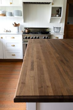 a wooden counter top in a kitchen with white cabinets