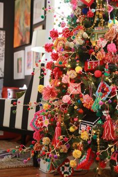 a brightly colored christmas tree is decorated with pom - poms and other ornaments