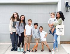 a group of children standing in front of a garage door with their mom and dad