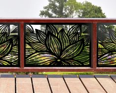 a wooden bench sitting next to a metal screen on top of a wooden deck with trees in the background