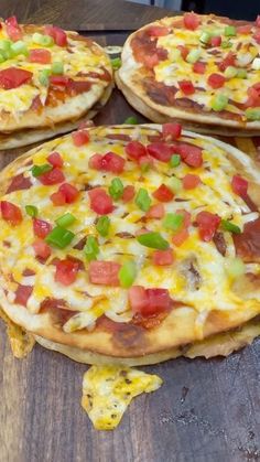 three pizzas with different toppings on them sitting on a wooden table next to each other