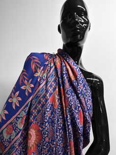 a black mannequin wearing a blue and red scarf with floral designs on it