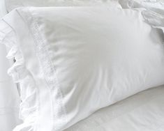 two white pillows with ruffled edges on a bed