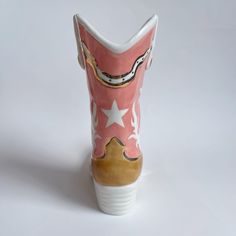 Description Introducing our stunning ceramic cowboy boot vase, a true masterpiece for Western enthusiasts! This eye-catching ceramic boot features intricate 22k gold designs, adding a touch of elegance to any space. Whether you're a cowboy at heart or simply appreciate unique decor, this vase is the perfect blend of style and functionality. Use it to display your favorite fresh flowers or as a standalone statement piece, this handmade ceramic cowboy boot vase is sure to capture the attention of Clay Cowboy Boot Match Holder, Pottery Cowboy Boot, Glass Cowboy Boot Vase, Cowgirl Boot Vase, Cowboy Boot Ceramic Vase, Ginger Jar Lamp, Studio Bag, Ceramic Supplies, Candle Crafts Diy