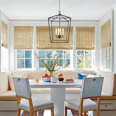 a dining room table with two chairs and a bench in front of the window,