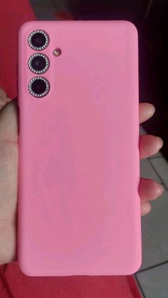 a person holding a pink cell phone in their hand with two buttons on the back