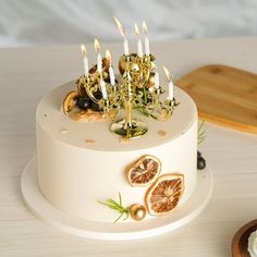 a white cake with candles and figurines on it sitting next to a cutting board