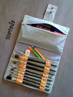 the pencils and markers are organized in a zippered pouch on top of a table