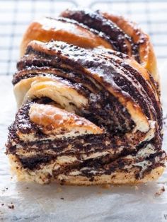 a pastry with chocolate and powdered sugar swirls on it's side, sitting on top of wax paper