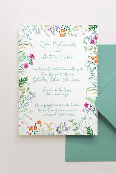 an open envelope with a floral design on it and a green envelope card next to it