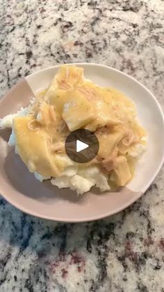 a white plate topped with mashed potatoes and gravy on top of a marble counter